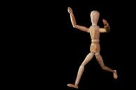 Wooden mannequin artfully posed against a black backdrop, showcasing movement.
